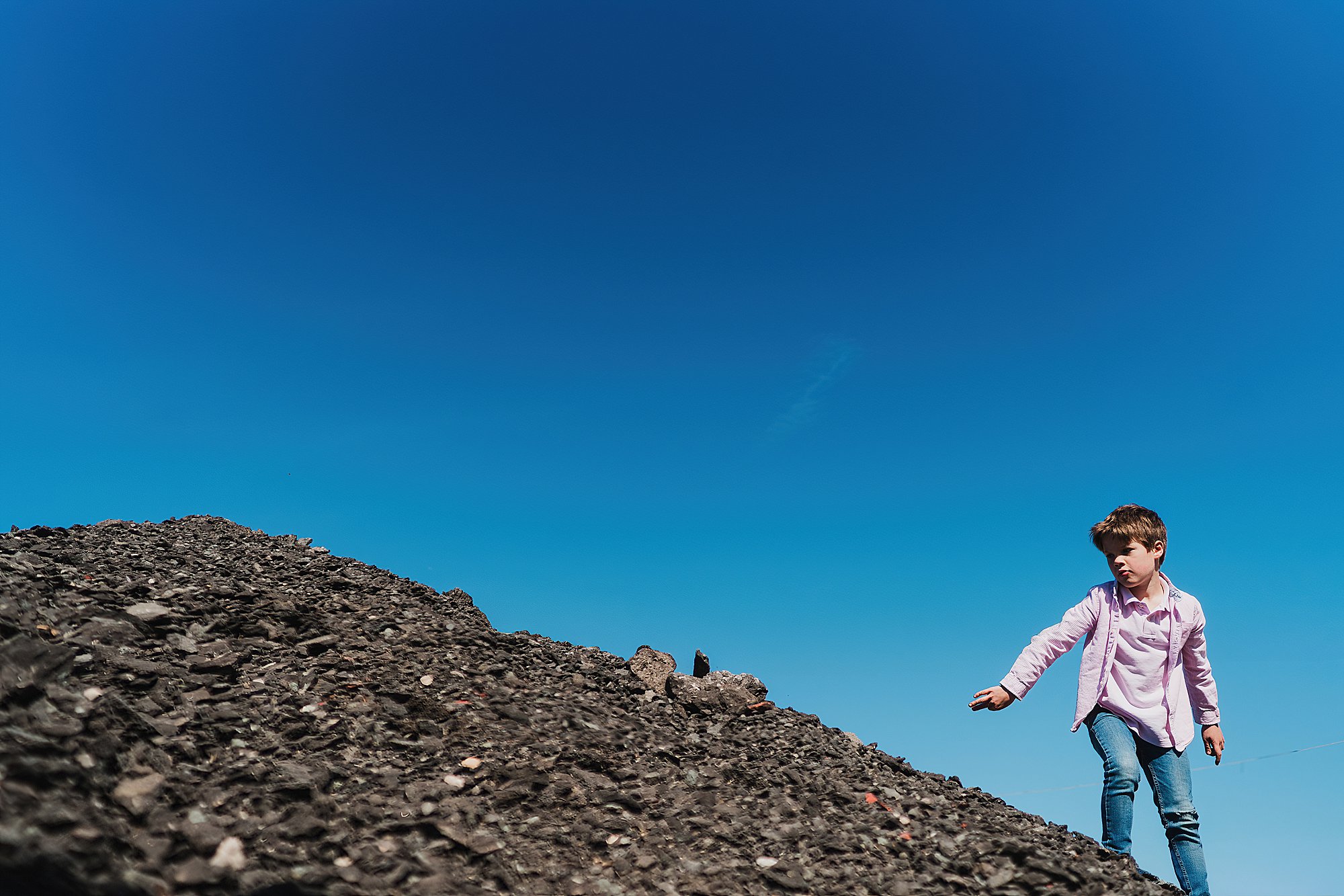 young boy climbing up shingle mound in Shropshire // Charlotte Giddings Photography