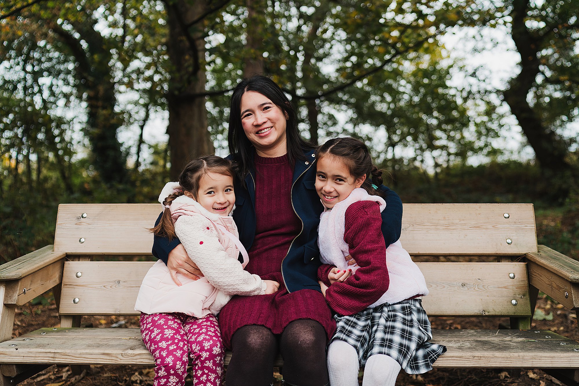 Mum sat on bench at Grinshill cuddling daughters on a bench // Shropshire Family Photographer