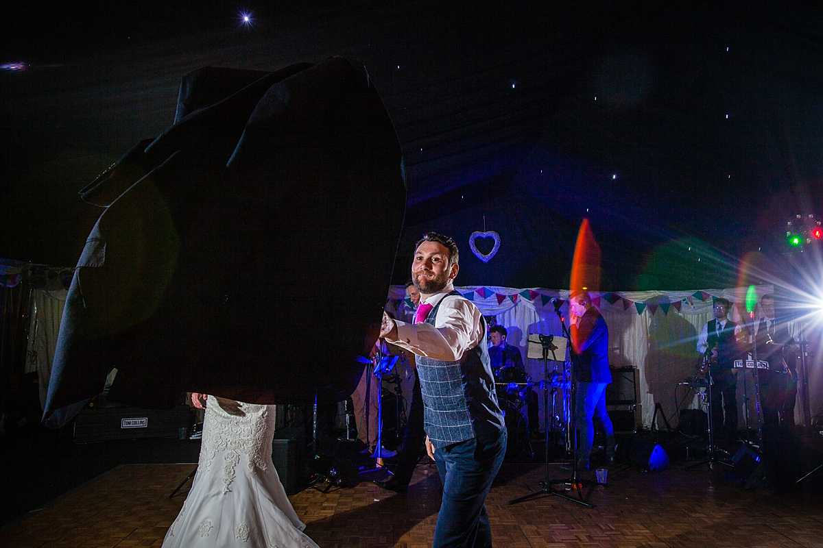 groom throwing his jacket as he is about to do the first dance at marquee wedding in Machynlleth 