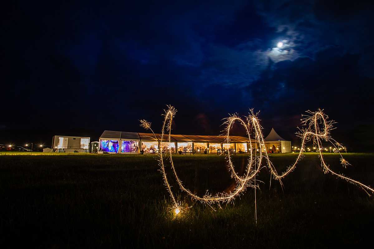 love written in sparklers with the marquee in the background for wedding in Machynlleth - charlotte giddings photography