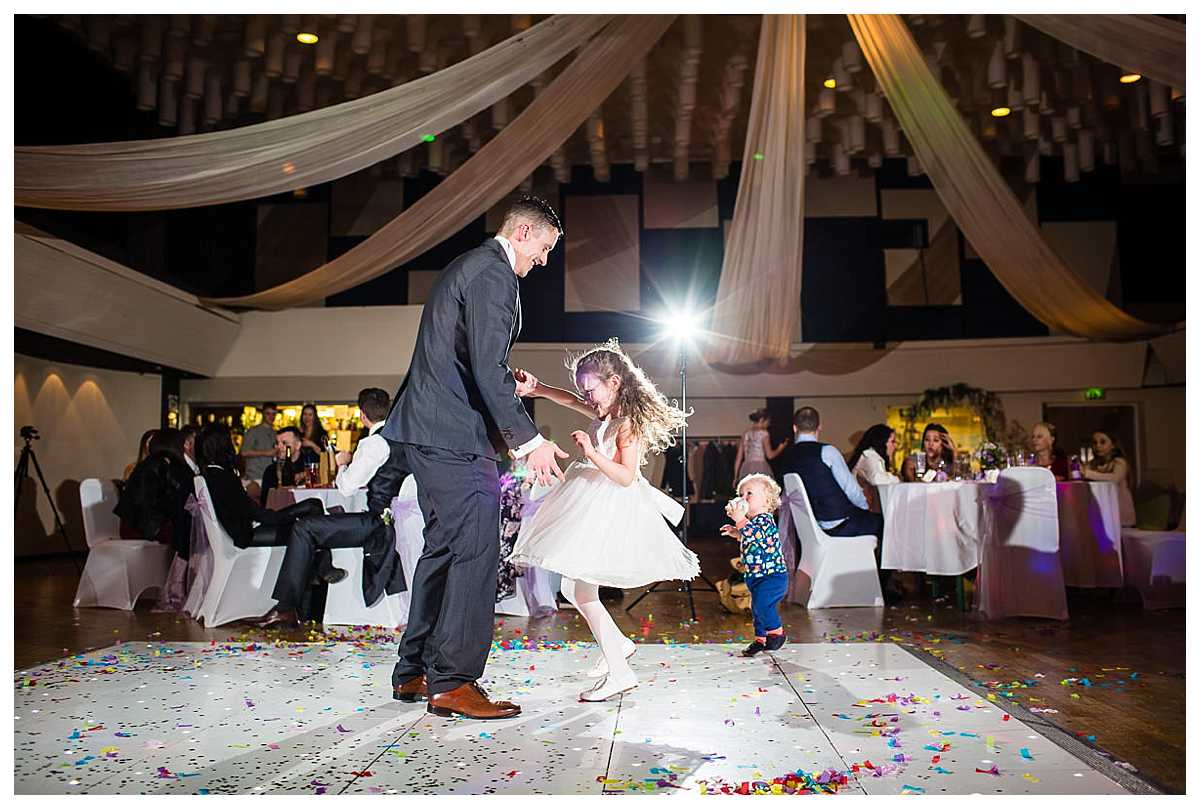 flower girl dancing with her dad who is the best man having a good time spinning her dress