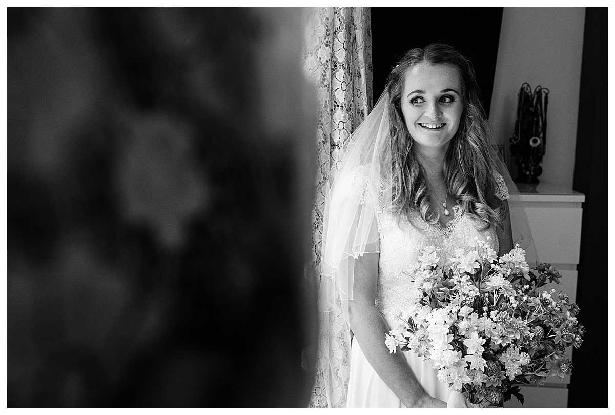 Bride looking out of the window excited to see wedding car pulling up, whitchurch shropshire wedding photographer