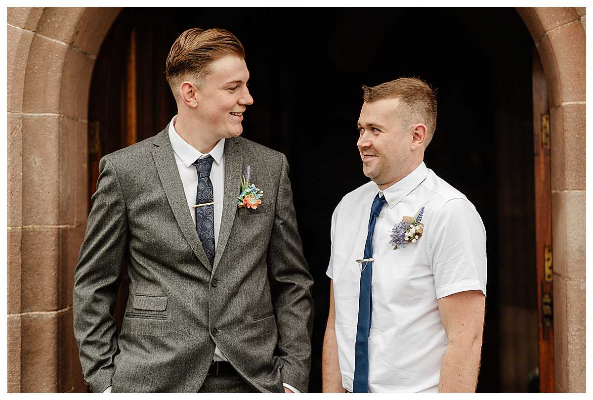 groom and best man laughing with each other in the door way at marbury church wedding whitchurch shropshire