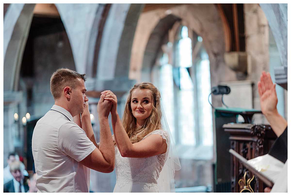 bride and groom holding hands as vicar conducts wedding blessing - shropshire wedding photography