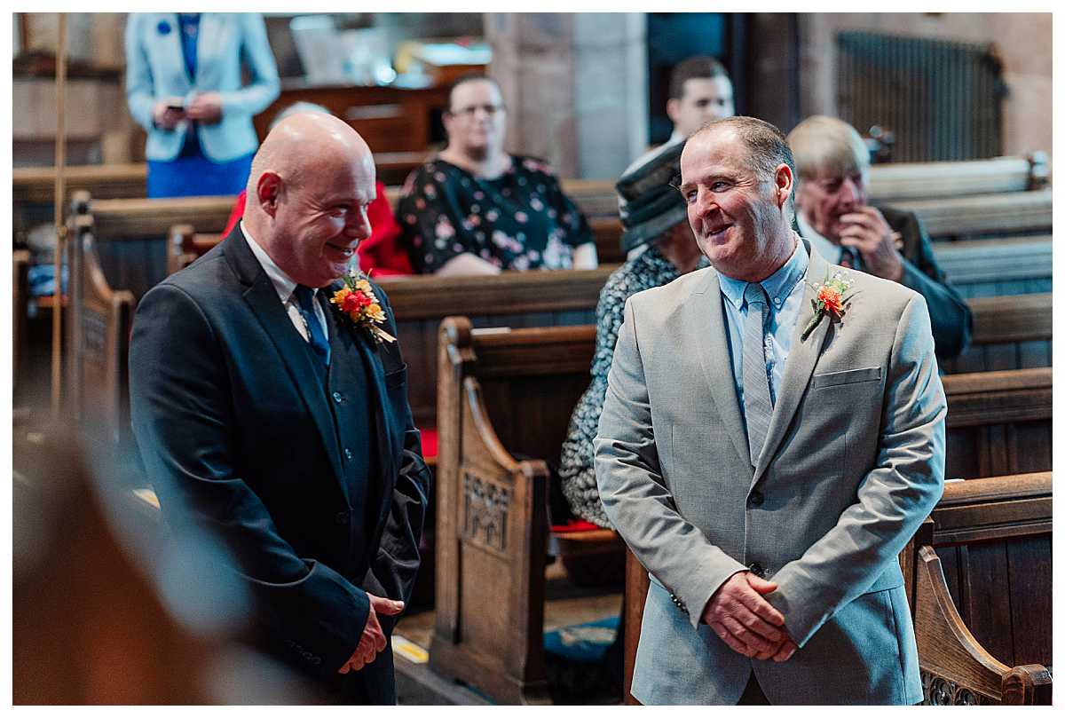 father of the bride and father of the groom exchanging banter as the bride and groom sign the register
