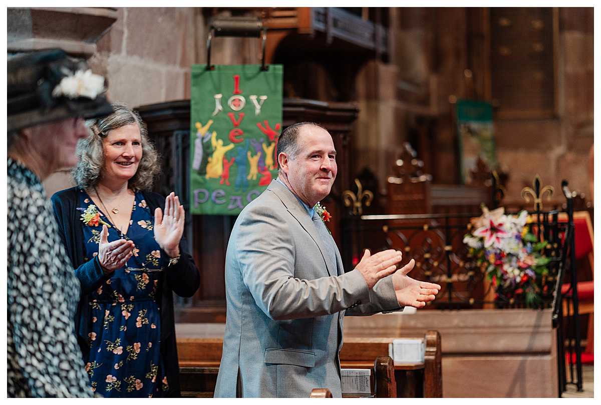 mother of the bride and father of the bride applauding the bride and groom as they walk down the aisle