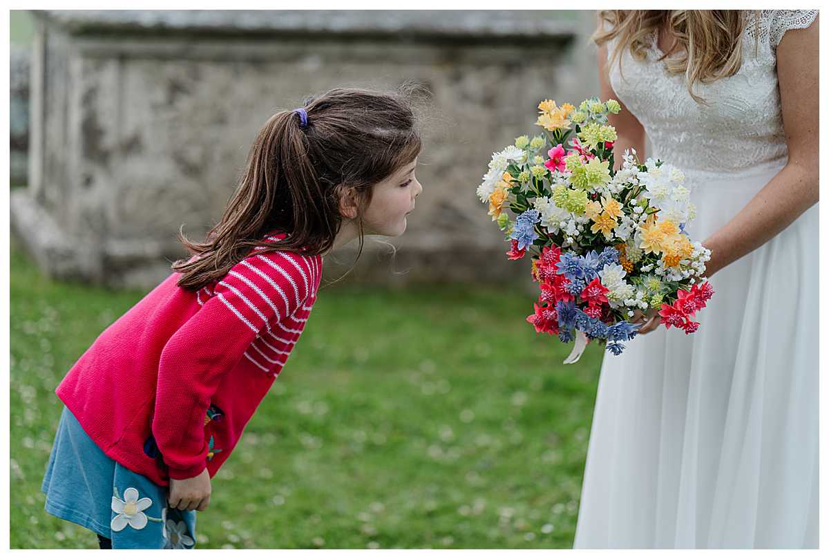 young cousin looking and smelling the bride's bouquet outside marbury church whitchurch shropshire