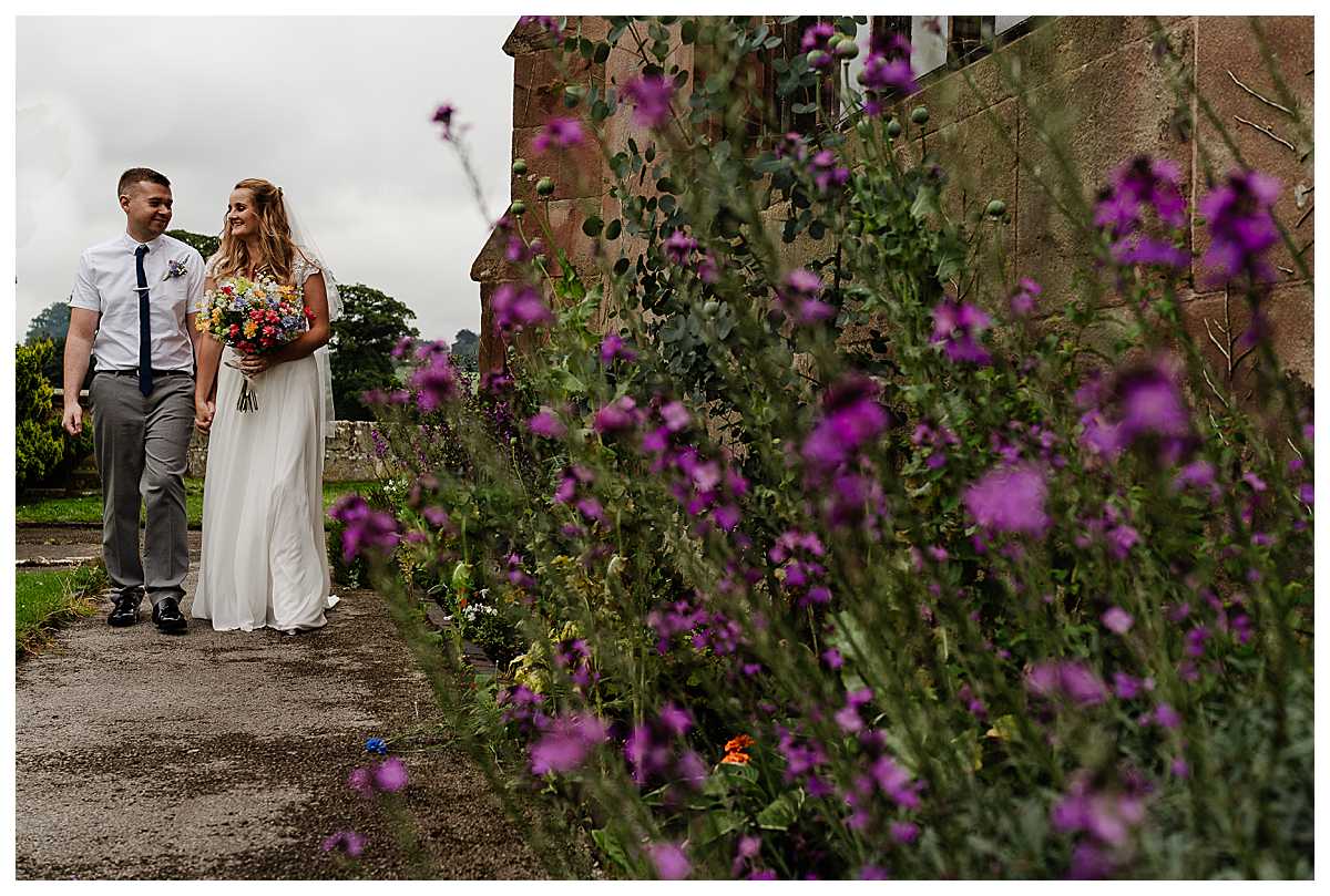 bride and groom walking around the outskirts of marbury church looking at one another, charlotte giddings photography