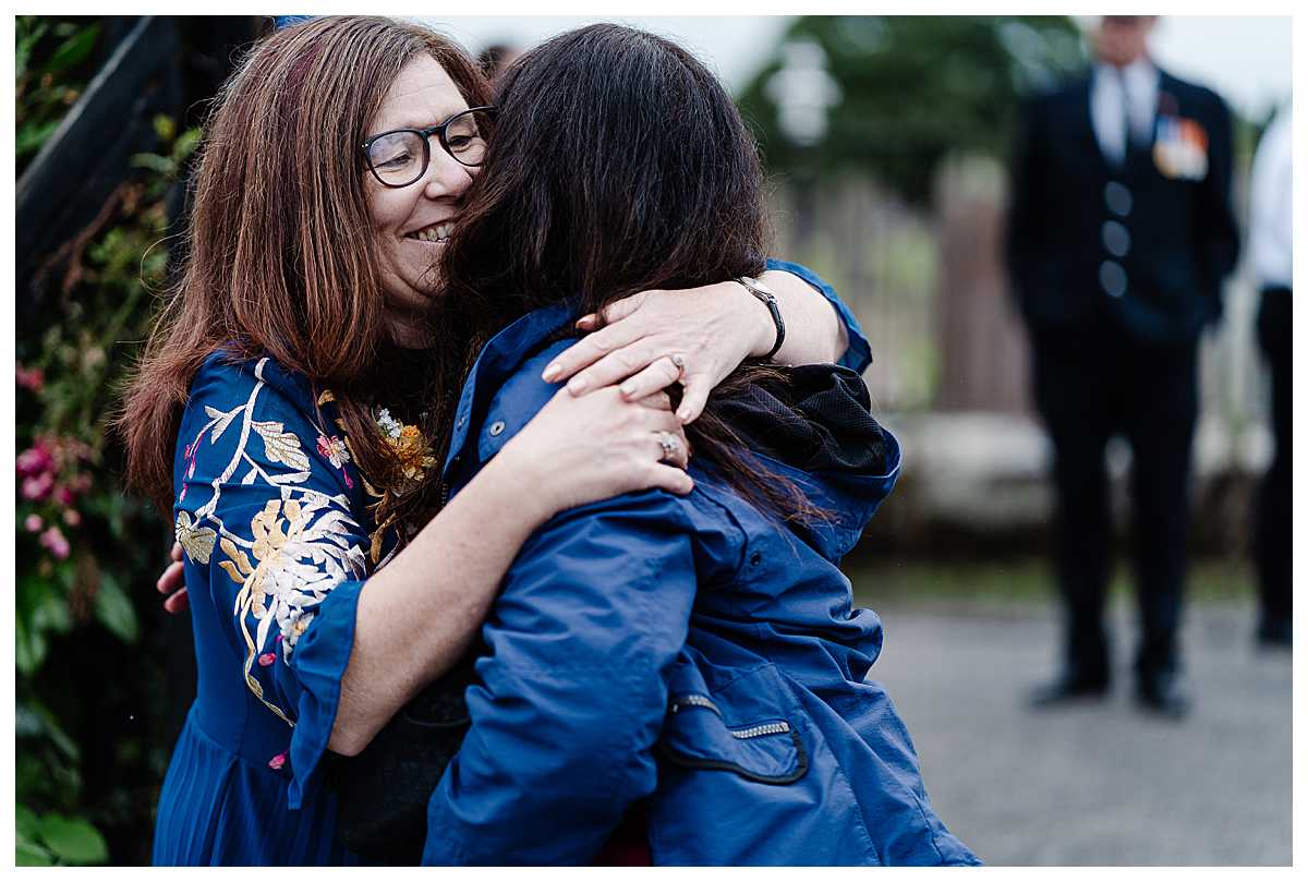 mother of the groom giving her sister a cuddle after wedding at marbury church whitchurch shropshire
