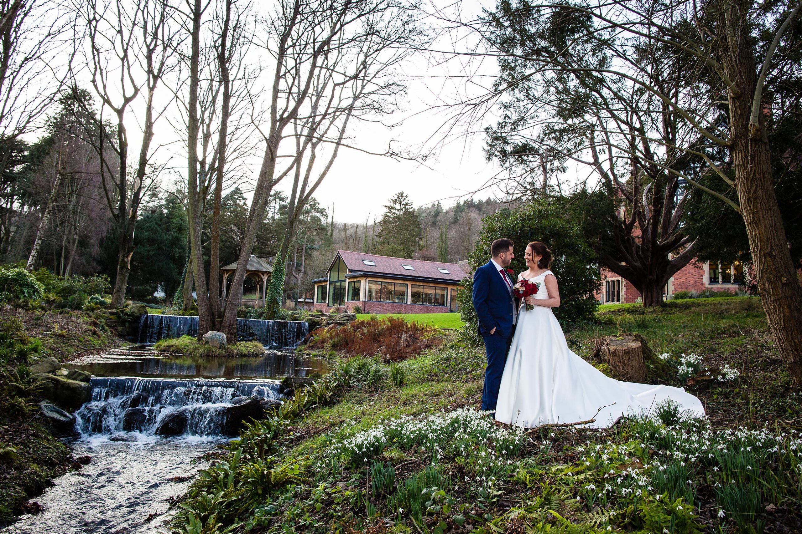 couple embracing by the waterfall and stream in the gardens of tyn dwr hall, llangollen