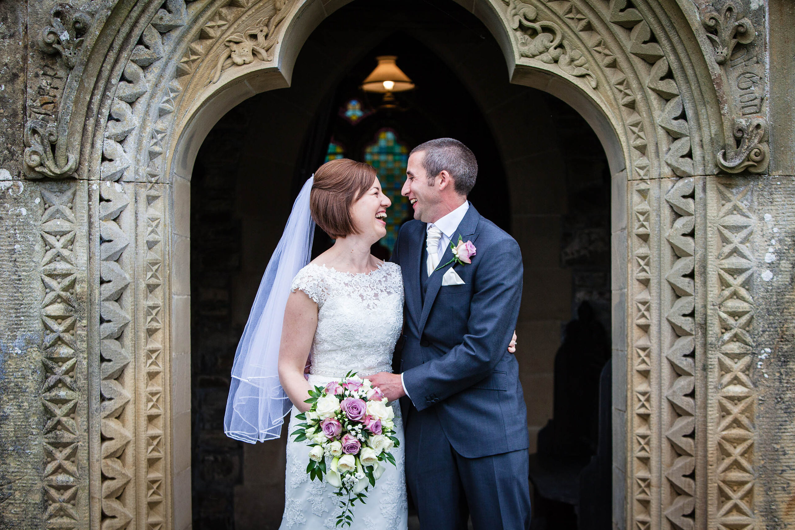 Bride and Groom laughing at one another in the door way of a church in Powys, Wales, welsh wedding photographer
