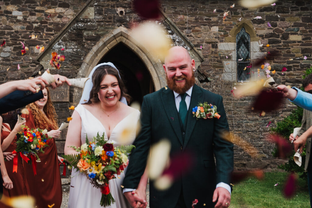 Confetti being thrown at the bride and groom outside Holy Trinity Church, Wistanstow / Charlotte Giddings Photography