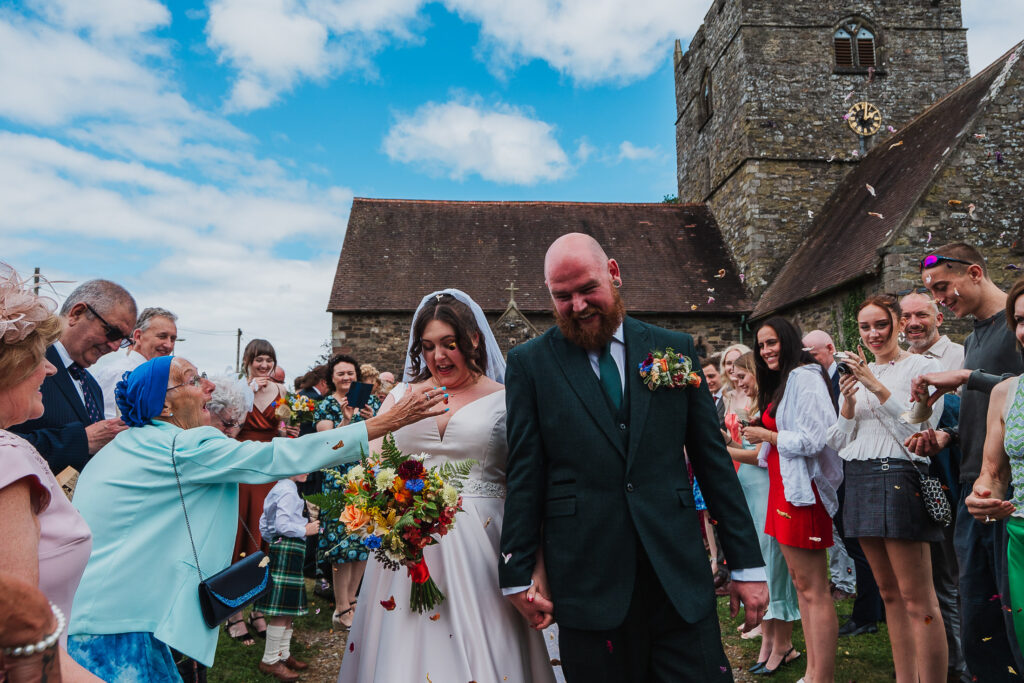 Nan throwing confetti down the bride's dress at Holy Trinity Church, Wistanstow, Craven Arms, Shropshire
