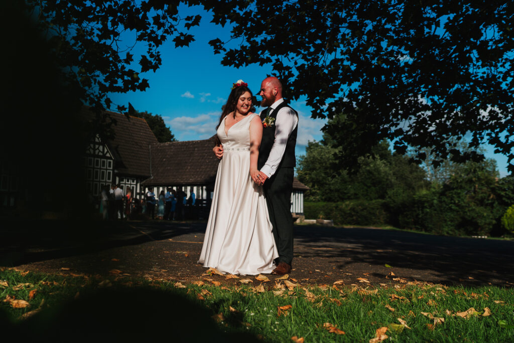 Bride and Groom giggling outside Wistanstow Village Hall in the evening golden hour sunshine / Shropshire Wedding Photography