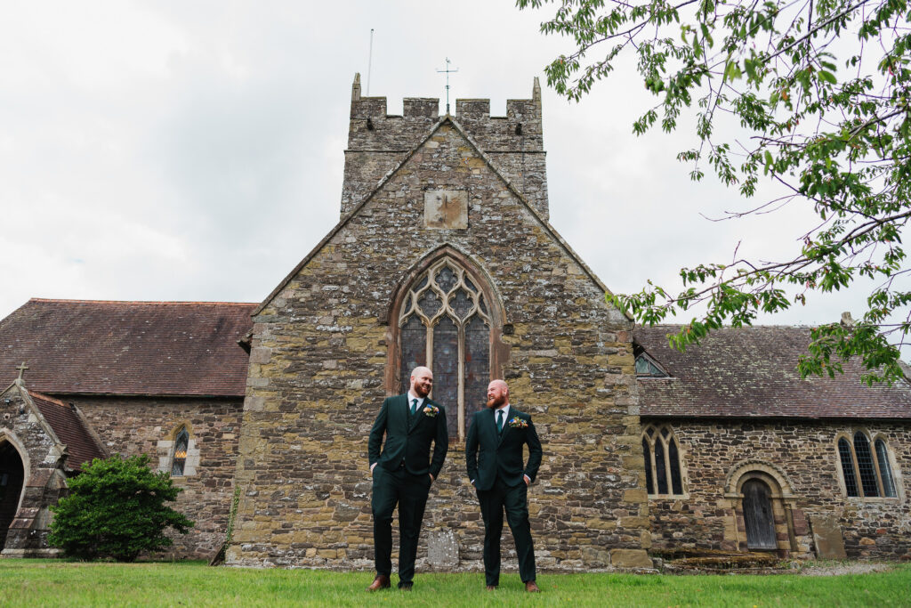 Groom with Best Man, dressed in green suits outside Wistanstow Church, Craven Arms Shropshire / Charlotte Giddings Photography

