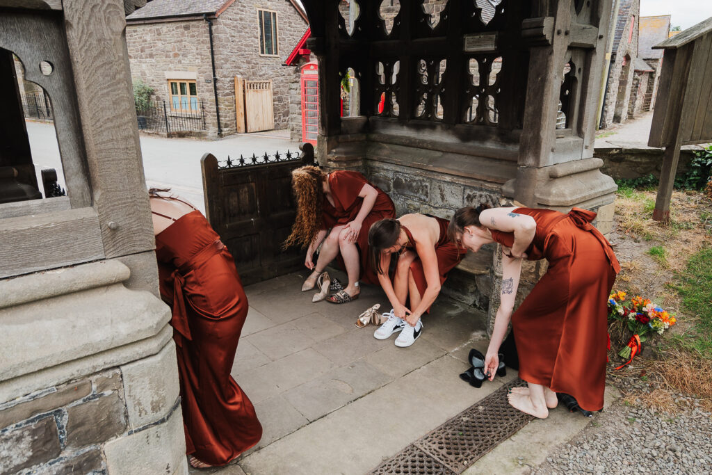 Bridesmaids changing their flat shoes into their heels to walk into church / practical over fashion / Charlotte Giddings Photography