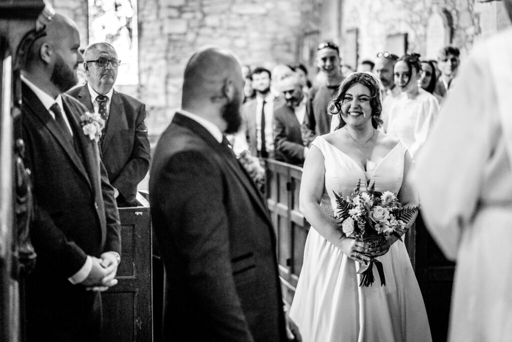 Bride beaming with happiness as she walks down the aisle and sees her groom for the first time in church