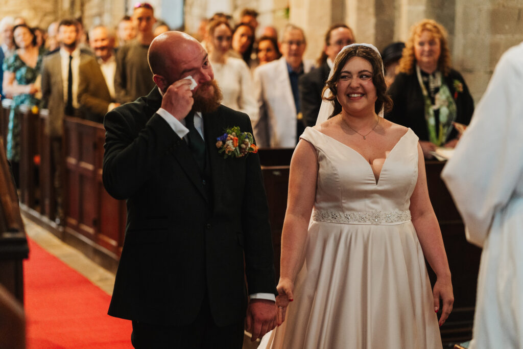 groom shedding a tear as he sees his bride at the top of the aisle at wistanstow church, south shropshire