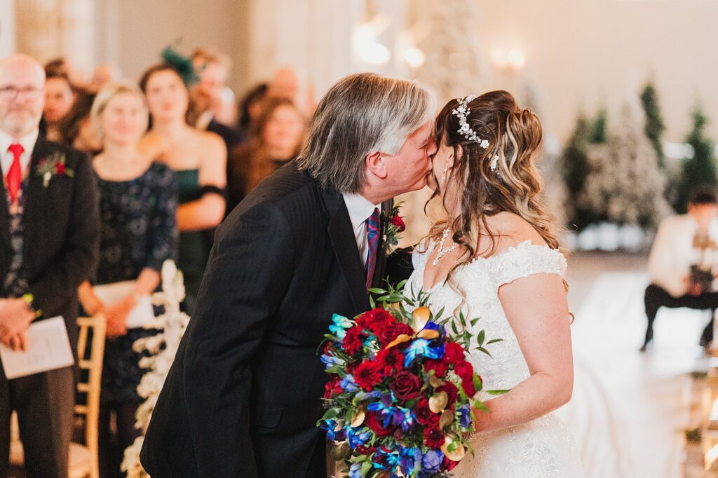 Dad giving his daughter a kiss at the top of the aisle as he is giving her away at The Cloisters, Bolton // Charlotte Giddings Photography