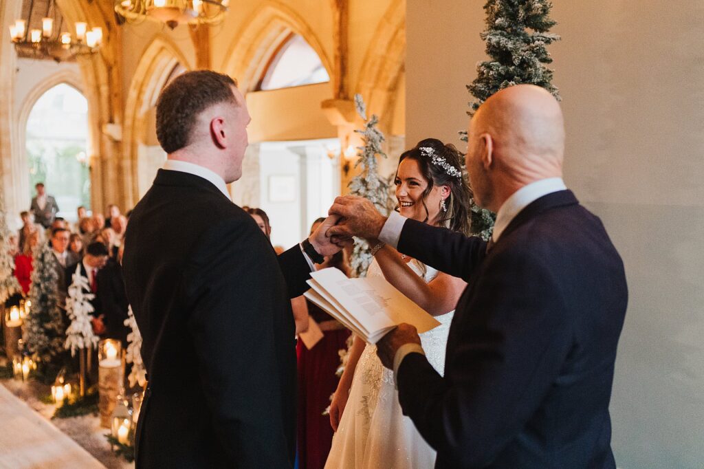 Bride and Groom looking at one another at the reverend is holding their hands praying for their marriage// Bolton Wedding Photographer