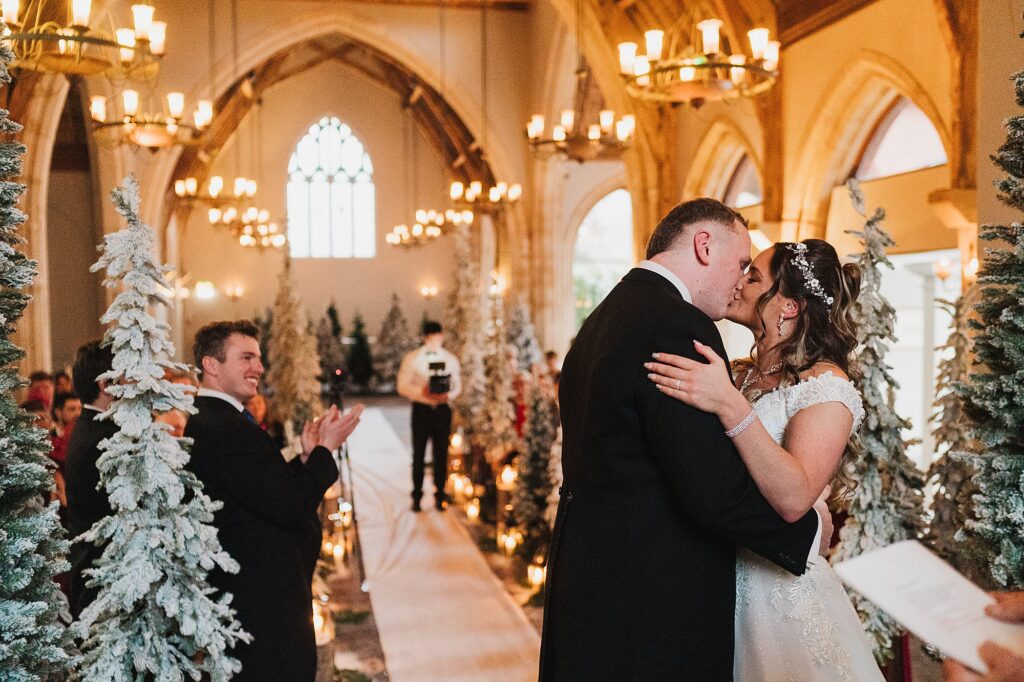 Bride and Groom having their first kiss as husband and wife at the top of the aisle with winter wonderland decor
