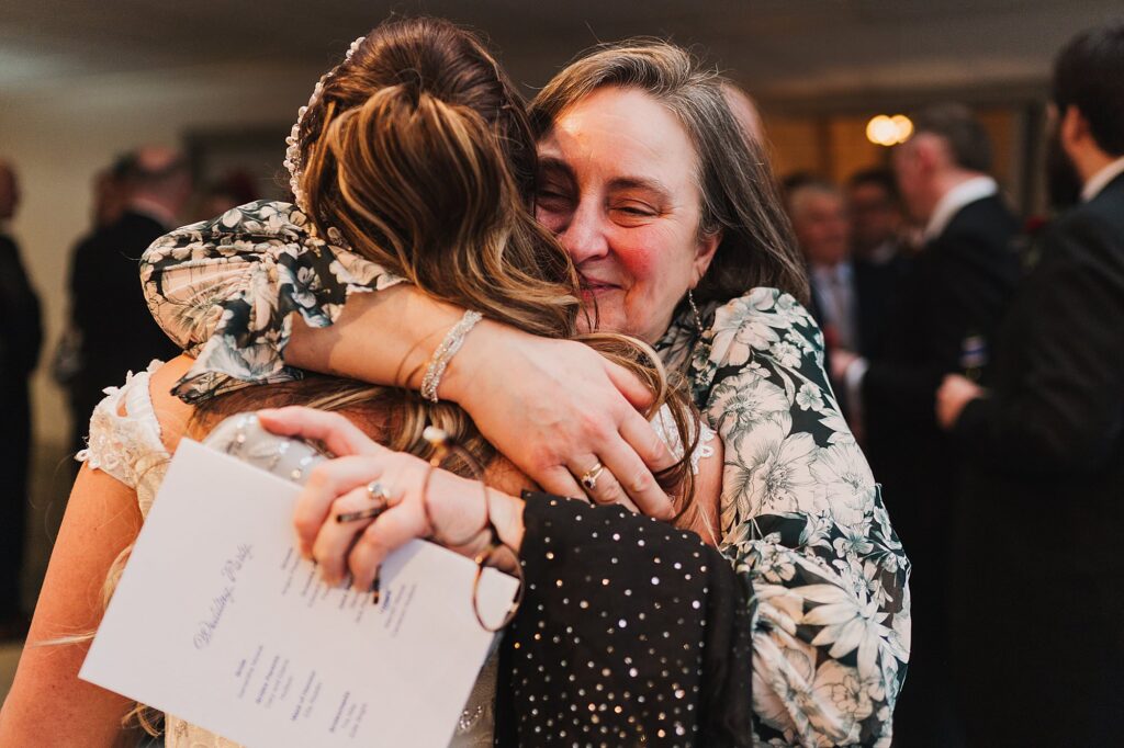 wedding guest embracing the bride after the wedding ceremony at The Cloisters in Bolton