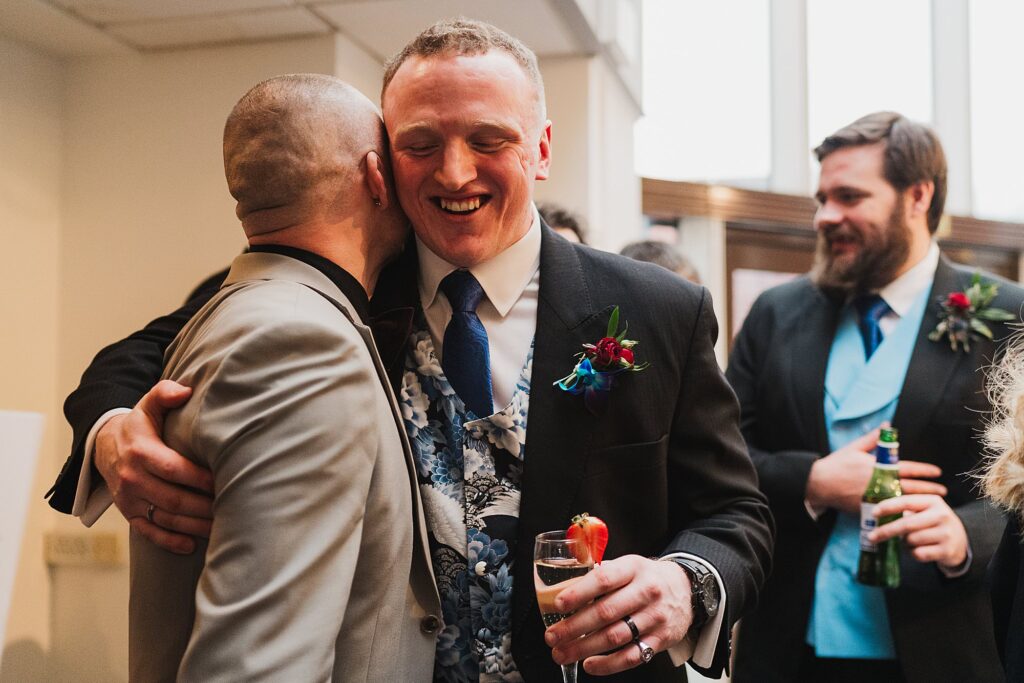 Groom giggling with a wedding guest as they congratulate them after the ceremony // Charlotte Giddings Photography