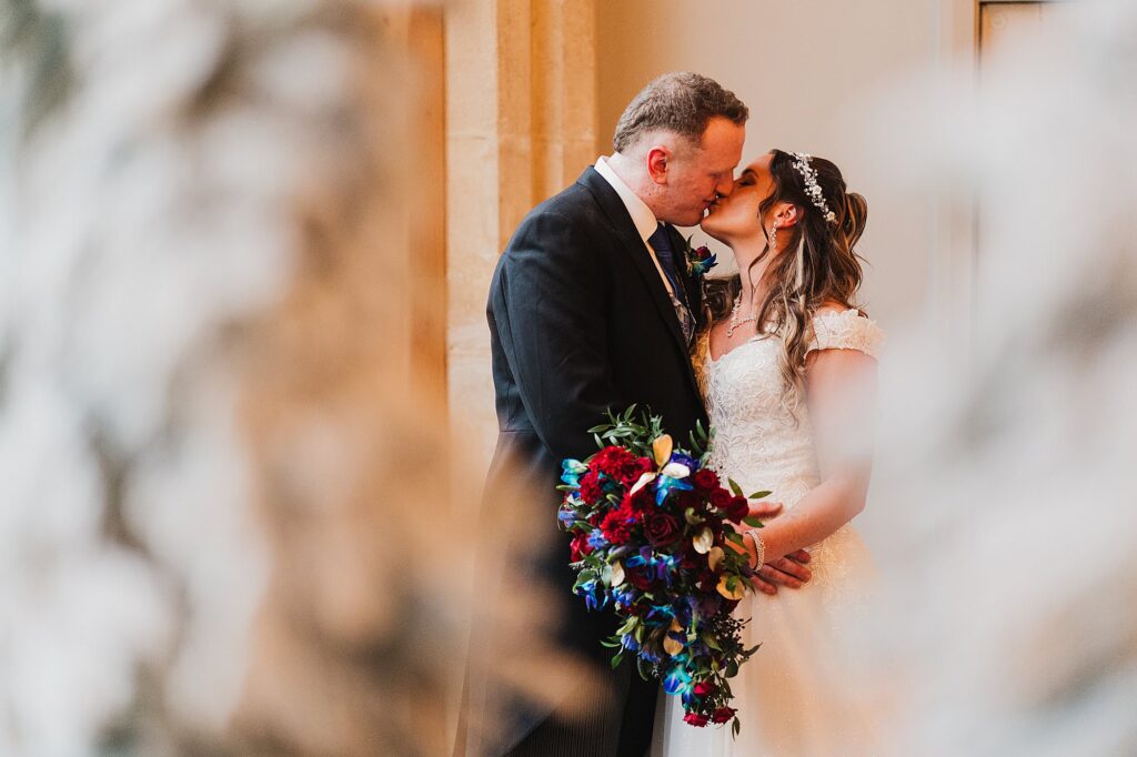 Bride and Groom having a kiss in the large window light at the Cloisters in Bolton // Bolton Wedding Photographer