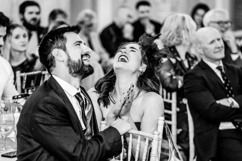 Groom's sister and partner giggling at the speeches at The Cloister's Wedding Venue, Bolton
