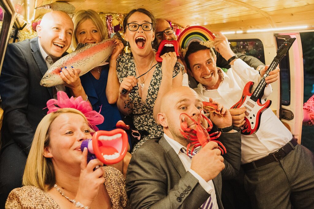 VW campervan Birdie Photo Booth filled with wedding guests having fun and posing for a photo with lots of funny props // Shropshire Wedding Photography