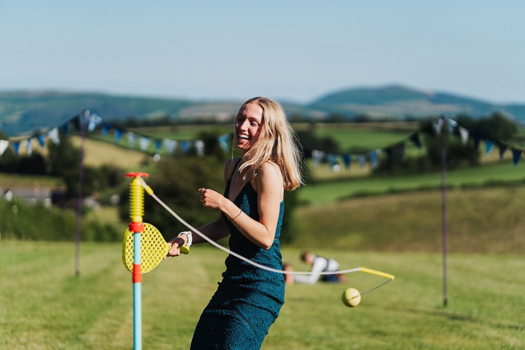 Female wedding guest playing bat and ball in the sunshine at a South Shropshire DIY wedding. Charlotte Giddings Photography