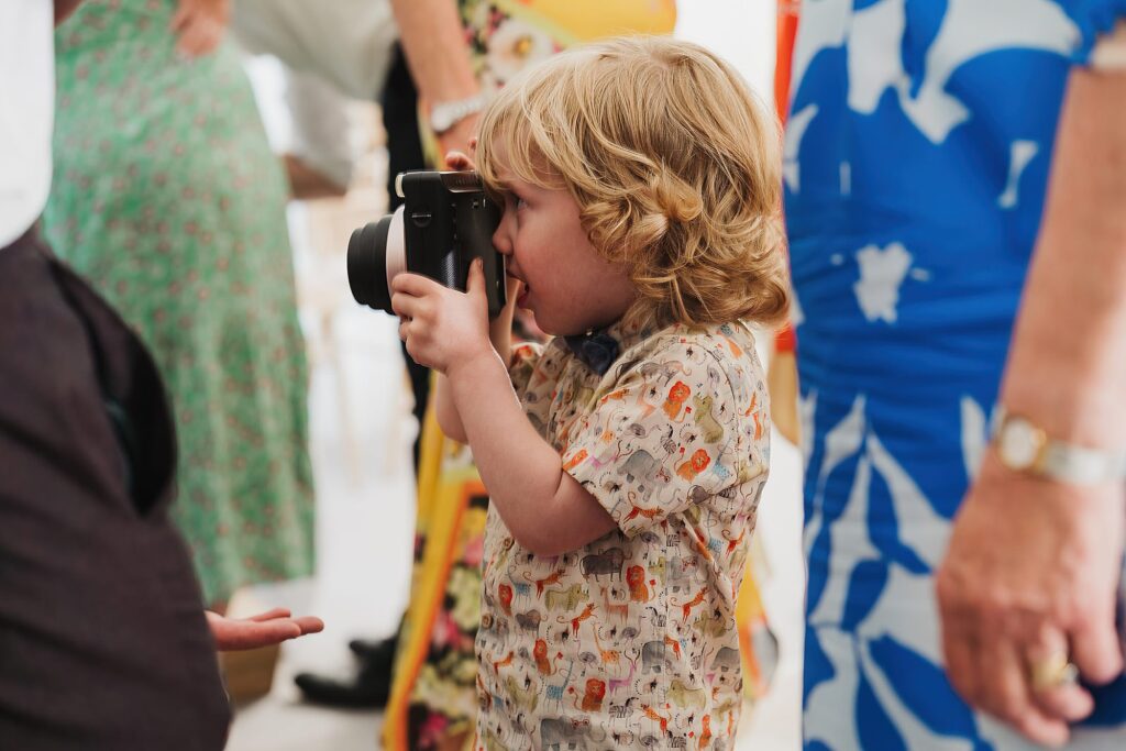 Young little boy going around a wedding taking photographs of wedding guests // Wedding Photographer Shropshire