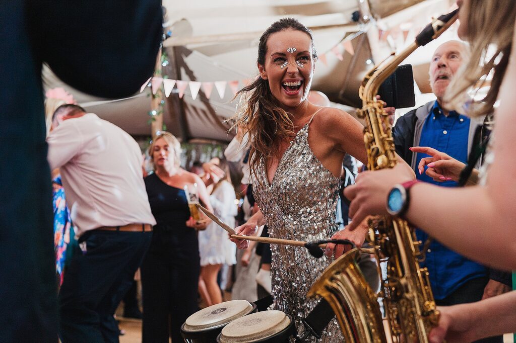 Wedding guests dancing around performers on the drums and saxophone have a super time // Cheshire Tipi Wedding