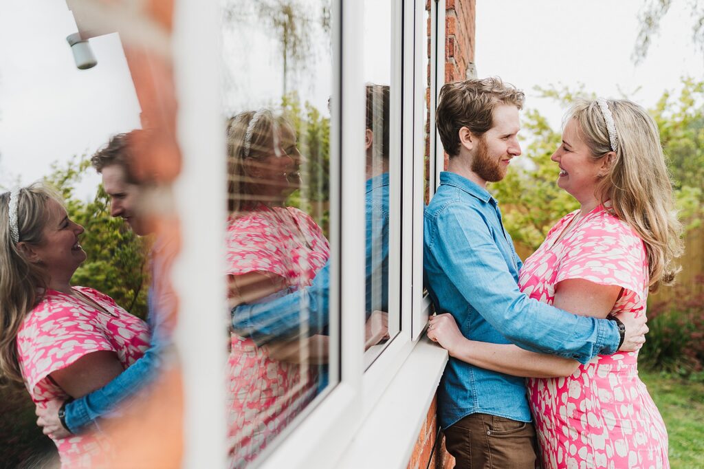 Bride and Groom to be cuddling up against the house with the reflection in the window // Charlotte Giddings Photography