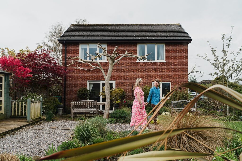 Bride and Groom to be walking through the garden holding hands with the house in the background // Wedding Photographer Shropshire
