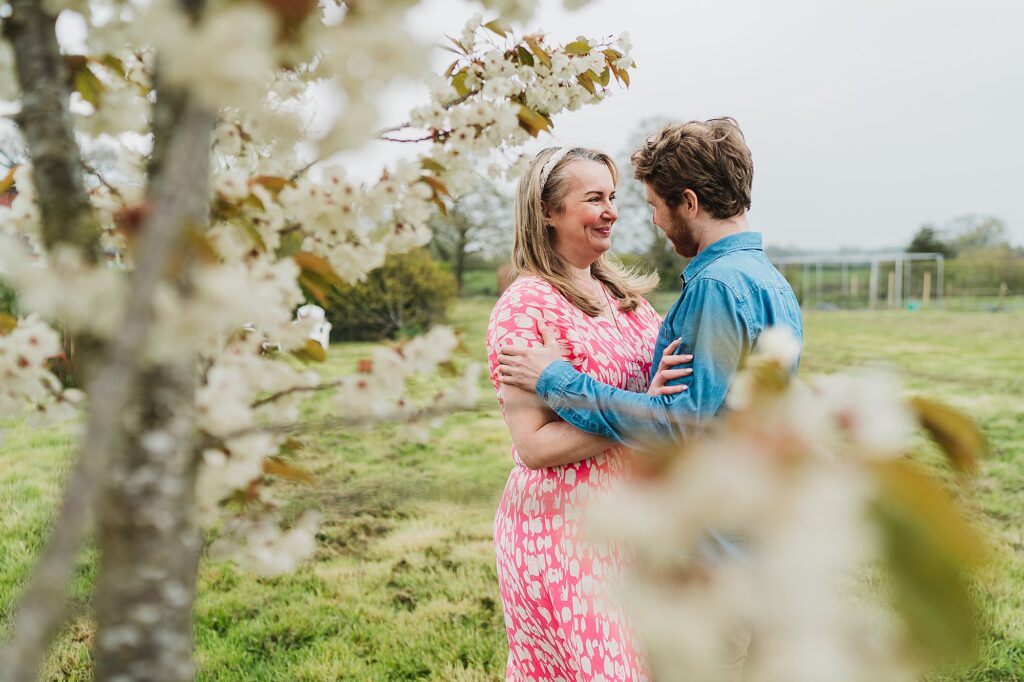 Bride and Groom amongst the blossoms of the trees in the garden at home // Combermere Abbey Wedding Photographer