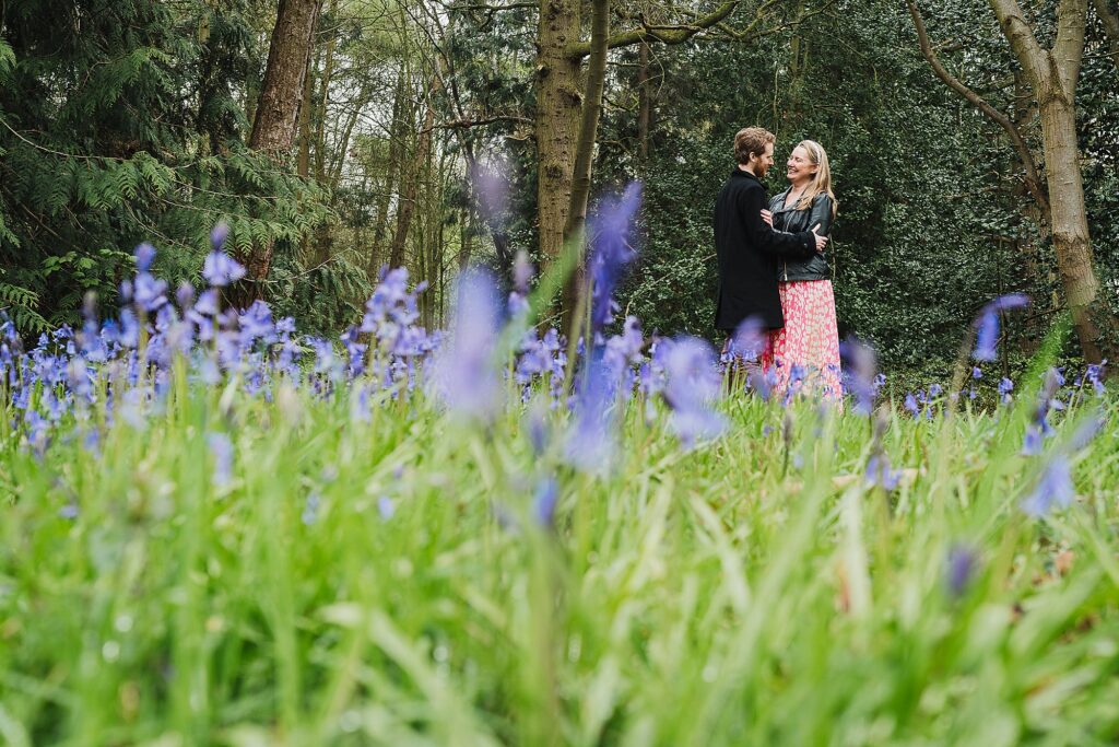 Bride and Groom giggling with each other while standing amongst a sea of Bluebells at Combermere Abbey