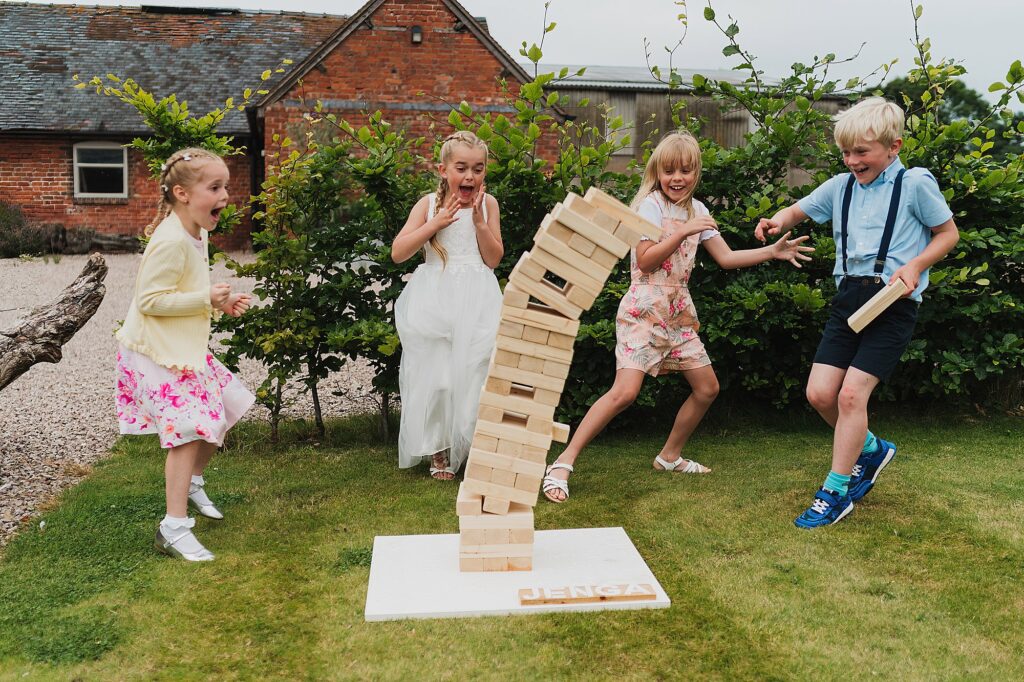 kids jumping away from a giant jenga falling at Pim Hill Barns // Shropshire wedding photographer