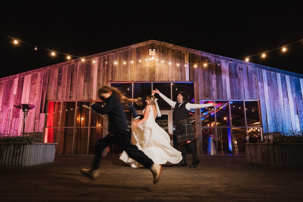Bride and Groom twirling round outside Grange Barn with a little boy running in the foreground // Grange Barn Wedding Photographer