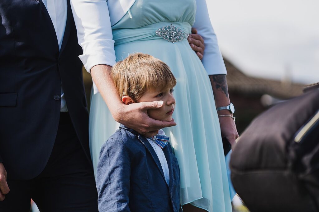 Young boy having his head craddled by his mothers hand during the speeches // DIY marquee wedding Wales