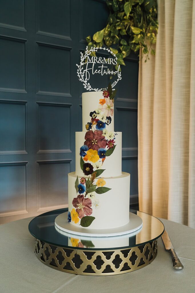 Beautiful three tiered cake decorated in summer blooms, displayed in the pavilion at Combermere Abbey, Shropshire