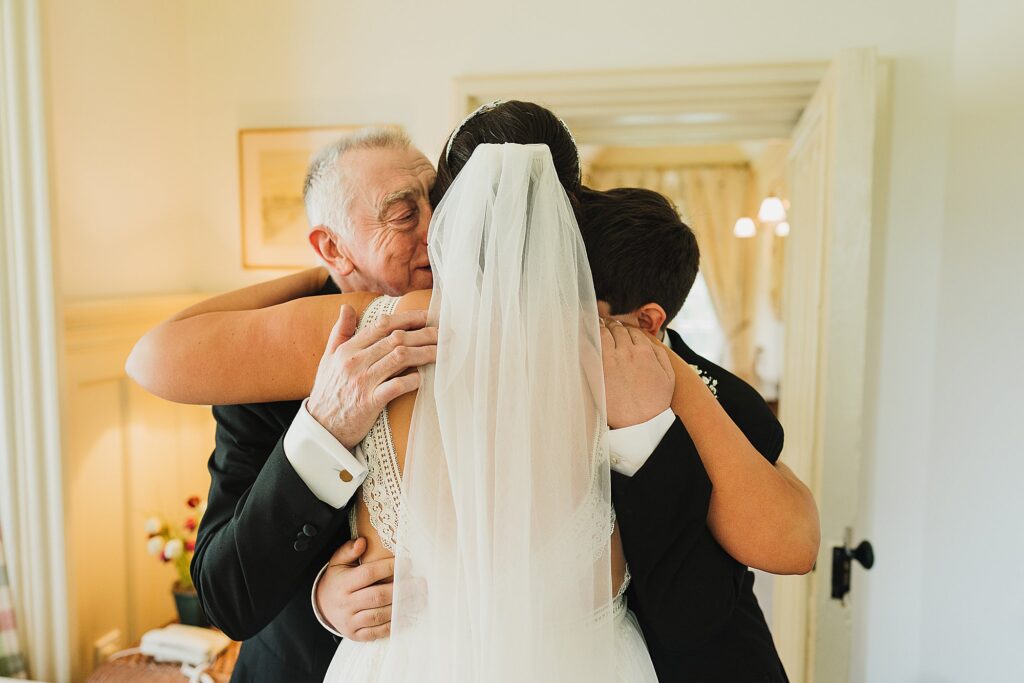 Double hug from Father of the Bride and Son of the Bride on the first look with the Bride at Combermere Abbey