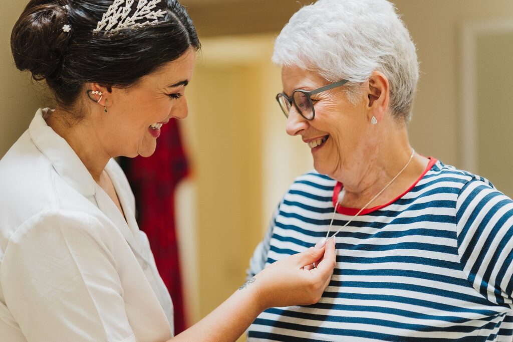 Bride looking at Mum's locket she is wearing as part of her outfit as Mother of the Bride at Combermere Abbey