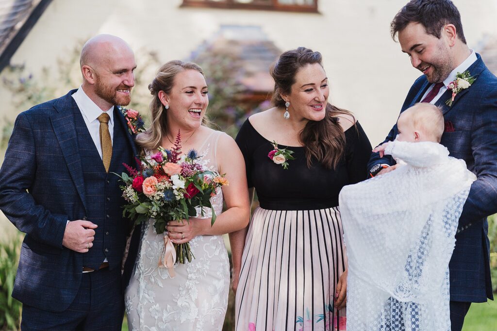 Bride and Groom cooing over little baby with its parents at home garden party in Cheshire // Charlotte Giddings Photography