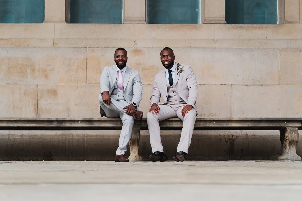 Groom and Best Man sitting on the bench outside St. George's Hall looking incredibly smart before the ceremony
