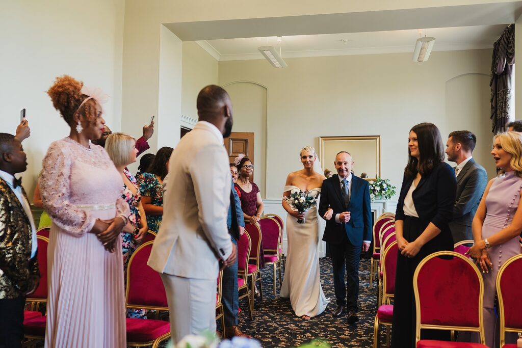 Bride walking down the aisle smiling at the Groom at St.George's Hall, Liverpool
