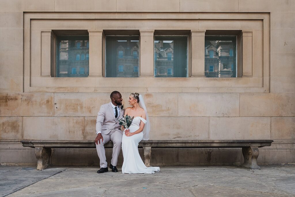 Bride and Groom sat on a bench outside of St George's Hall after getting married and looking incredibly happy! Charlotte Giddings Photography
