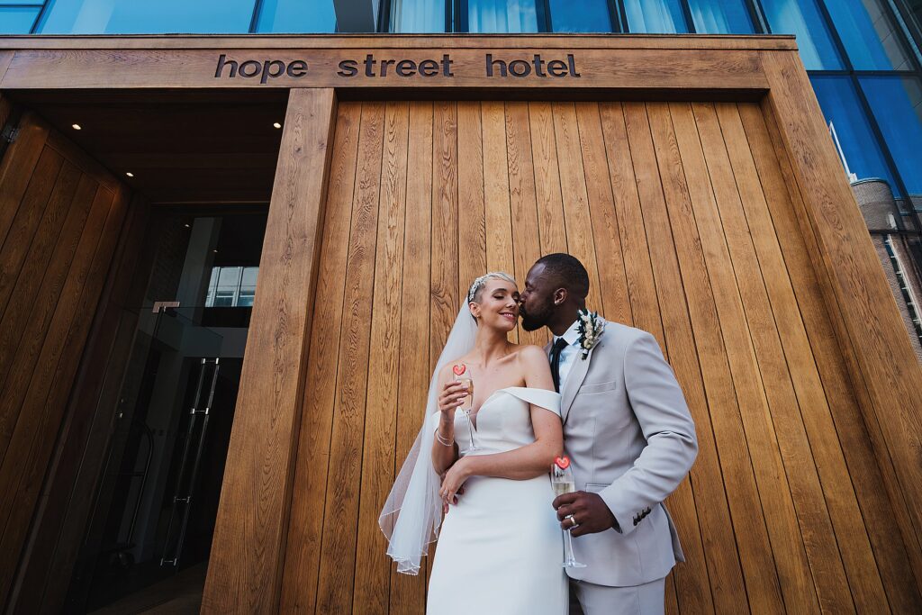 Groom kissing the bride on her cheek while cuddling outside of Hope Street Hotel, Liverpool// Liverpool Wedding Photographer
