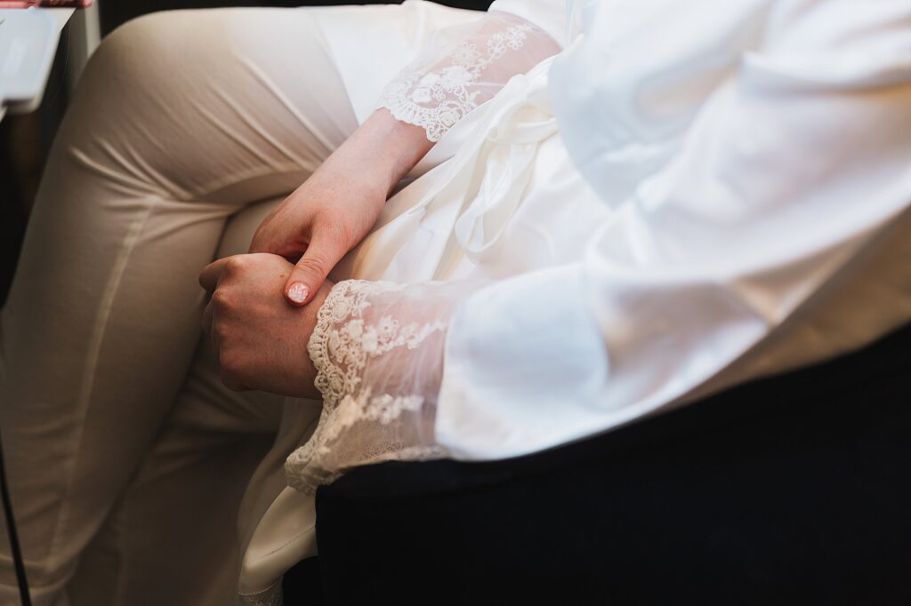 Bride sitting in the makeup chair in lace trimmed pyjamas relaxing before she gets changed into her wedding dress