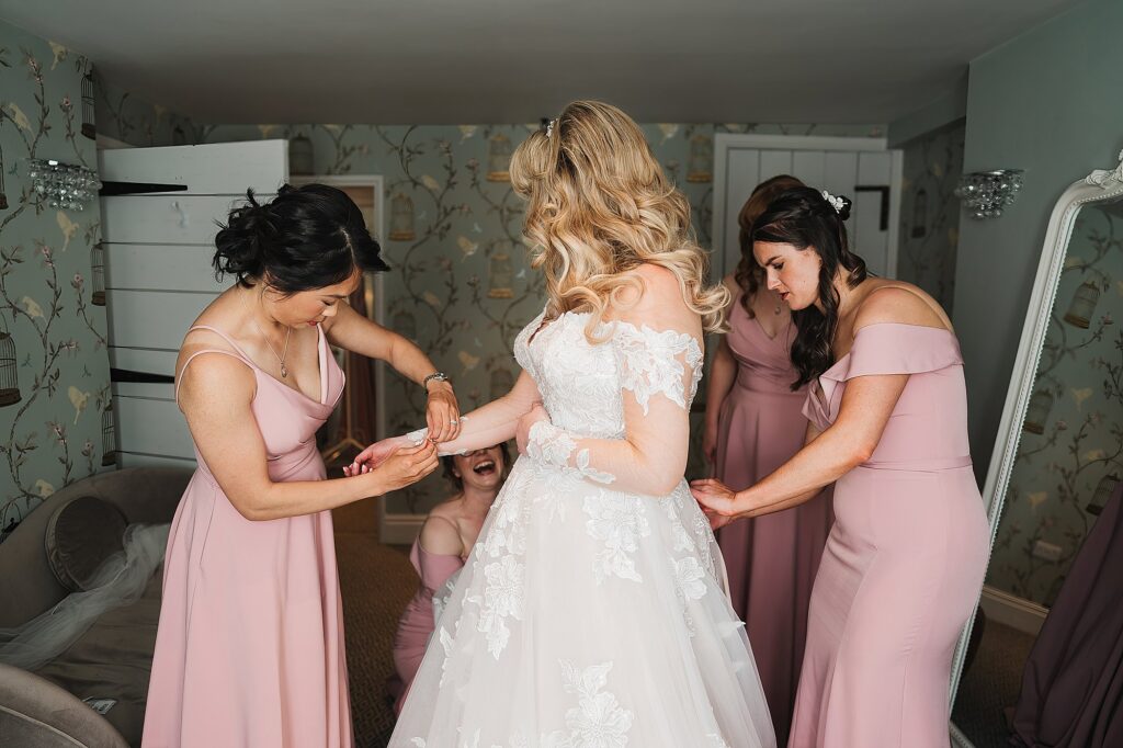 Bride in her dress with help from her bridesmaids at Combermere Abbey
// Charlotte Giddings Photography